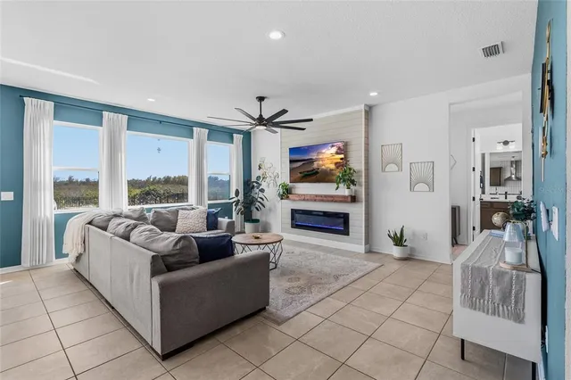 a view of a dining room and livingroom with furniture wooden floor a rug a fireplace and a chandelier