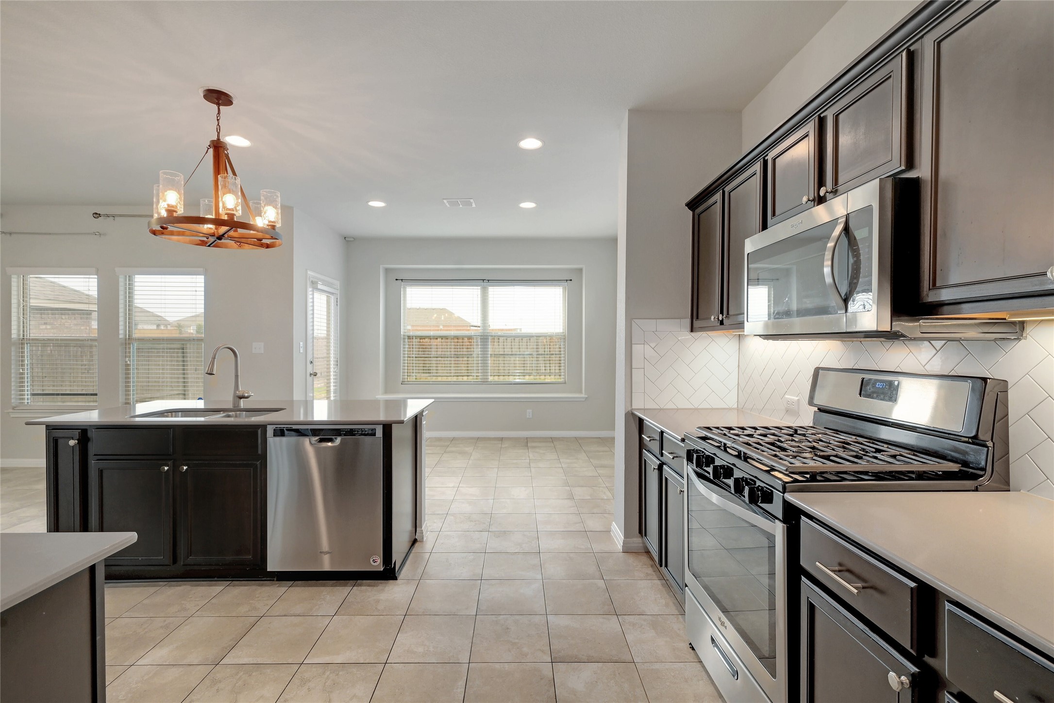 702 Nautical Loop Kyle, TX 78640 - Photo 12 of 27 The kitchen features dark cabinetry, stainless steel appliances including a gas range and microwave, and a tiled backsplash
