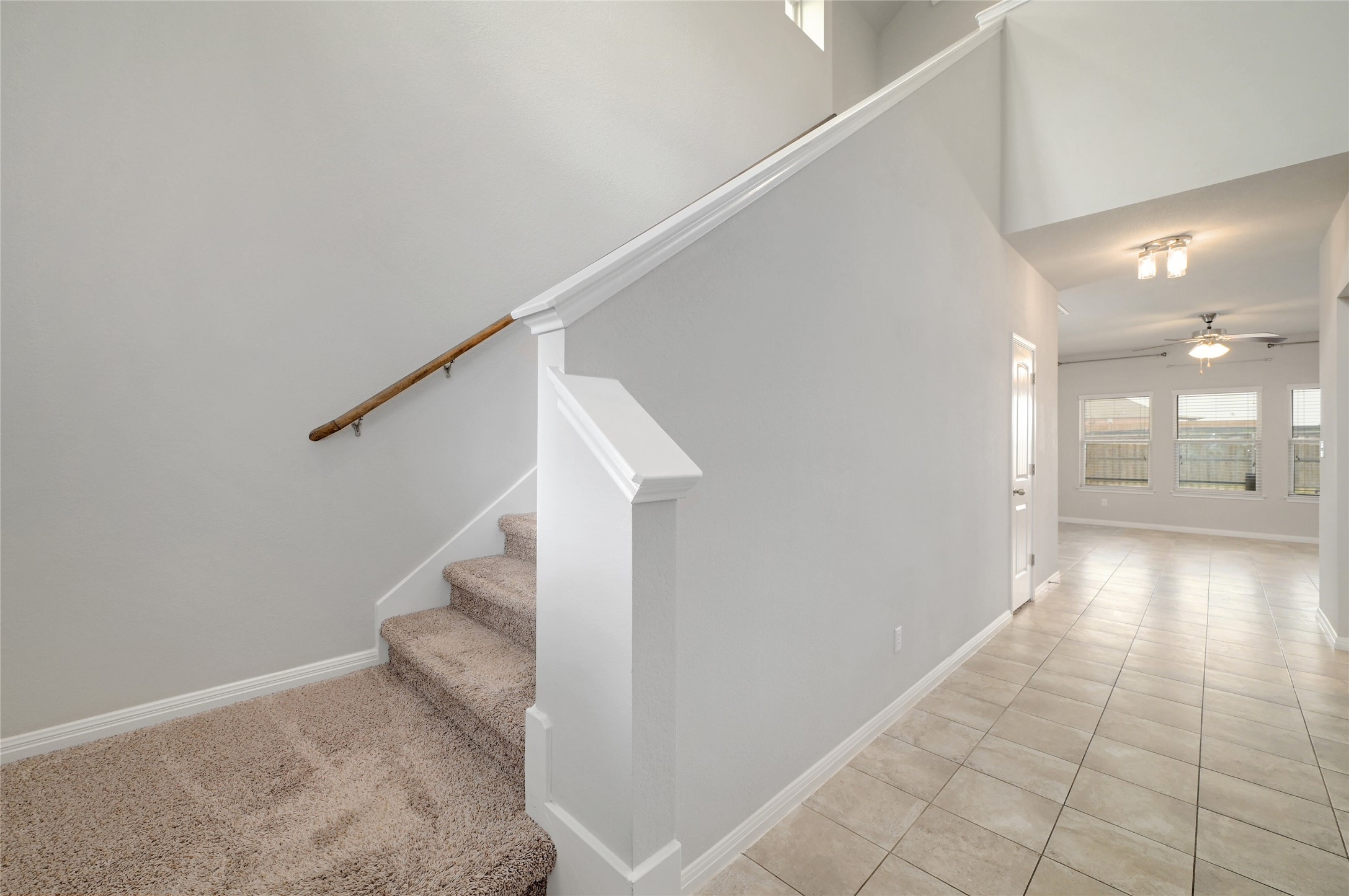 702 Nautical Loop Kyle, TX 78640 - Photo 14 of 27 Entryway featuring tile flooring, a carpeted staircase with a wooden handrail, and views into a living area with large windows