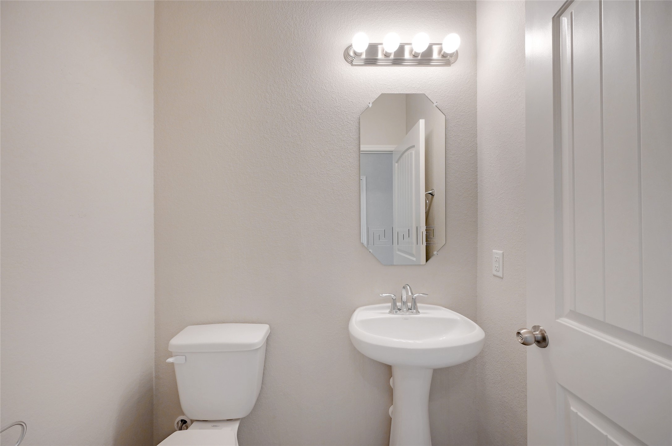 702 Nautical Loop Kyle, TX 78640 - Photo 15 of 27 Bathroom featuring a white pedestal sink, a toilet, a decorative mirror, and a modern light fixture with four bulbs