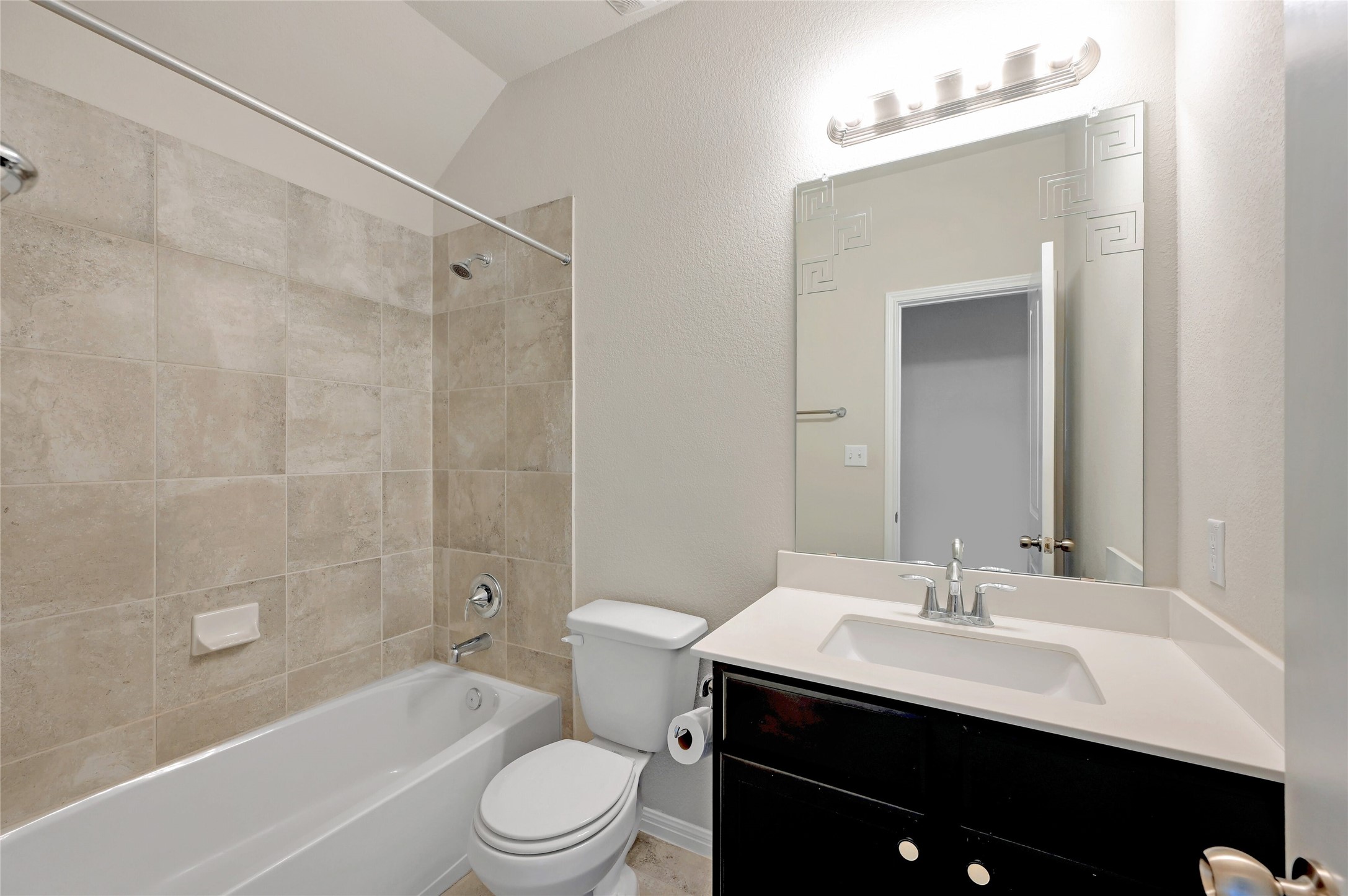 702 Nautical Loop Kyle, TX 78640 - Photo 23 of 27 The bathroom features a vanity with a white countertop and a dark wood cabinet, a mirror with an etched design, a shower and bathtub combination with tiled walls, and a toilet