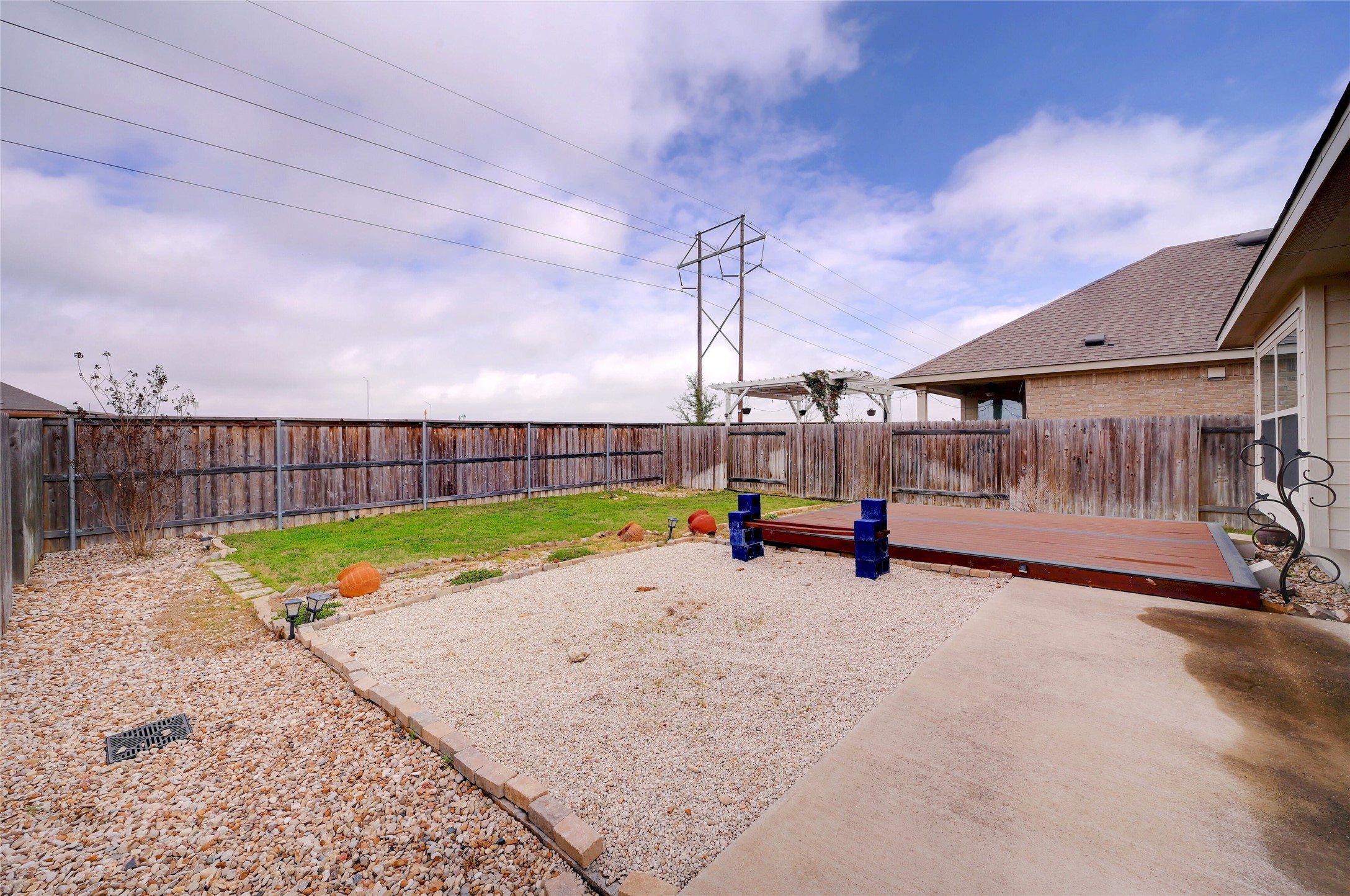 702 Nautical Loop Kyle, TX 78640 - Photo 25 of 27 The backyard features a wooden fence, a gravel area, a grass section, and a deck