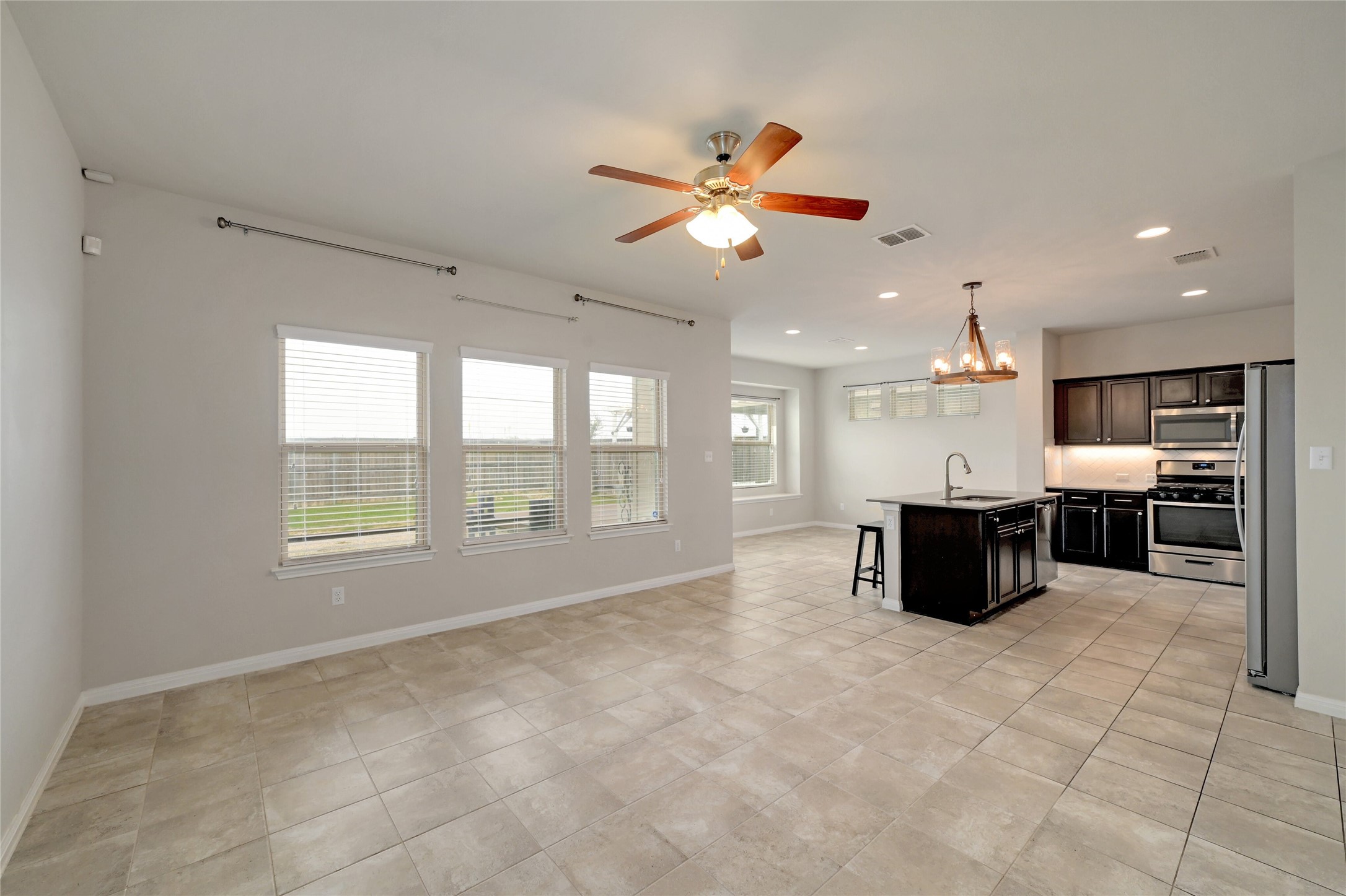 702 Nautical Loop Kyle, TX 78640 - Photo 4 of 27 Spacious living area featuring tile flooring, a ceiling fan, and large windows with blinds