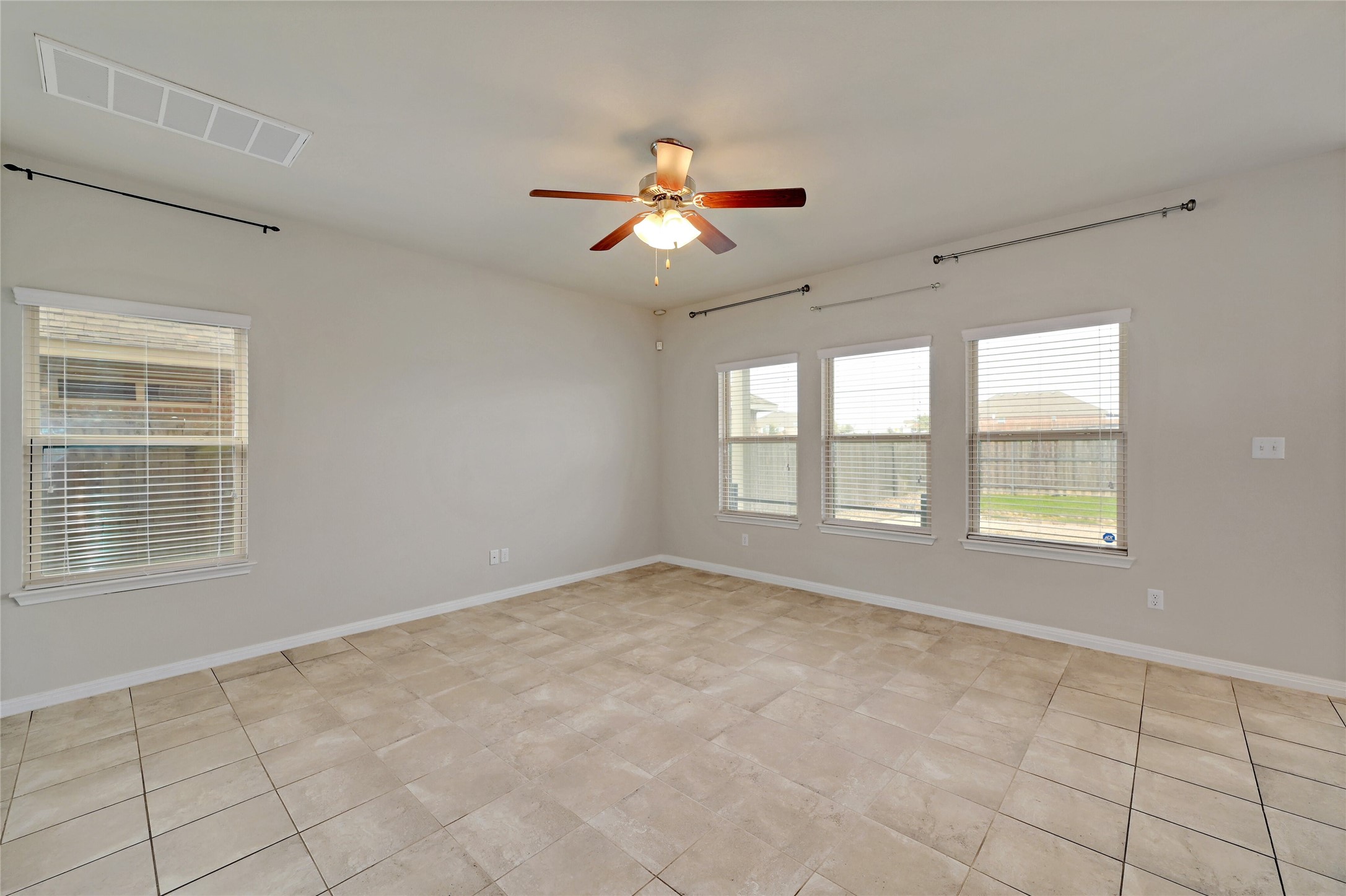 702 Nautical Loop Kyle, TX 78640 - Photo 7 of 27 Expansive room featuring light-colored tiled flooring, a ceiling fan, and multiple windows providing natural light