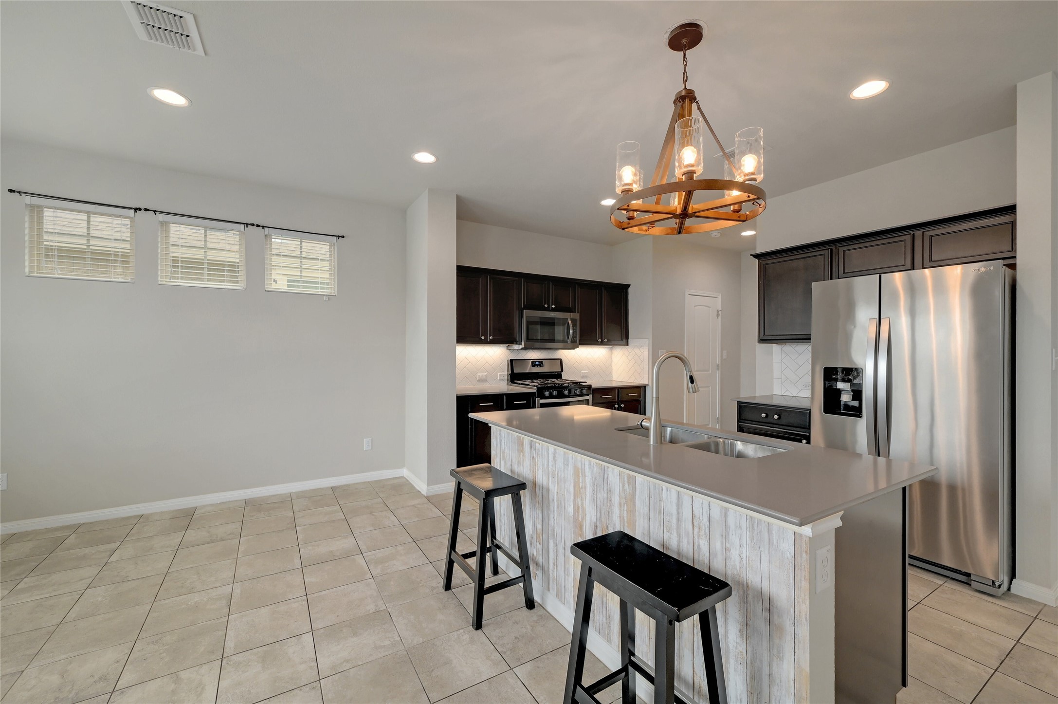 702 Nautical Loop Kyle, TX 78640 - Photo 9 of 27 The kitchen features dark wood cabinetry, stainless steel appliances, and a central island with a sink and seating