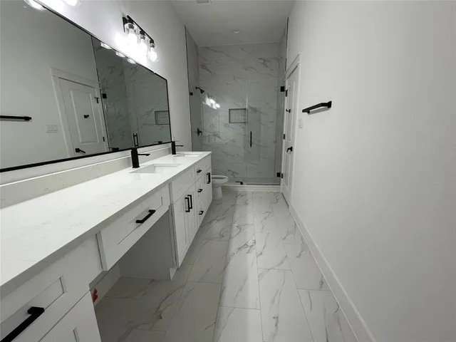 a spacious bathroom with a double vanity sink mirror and shower