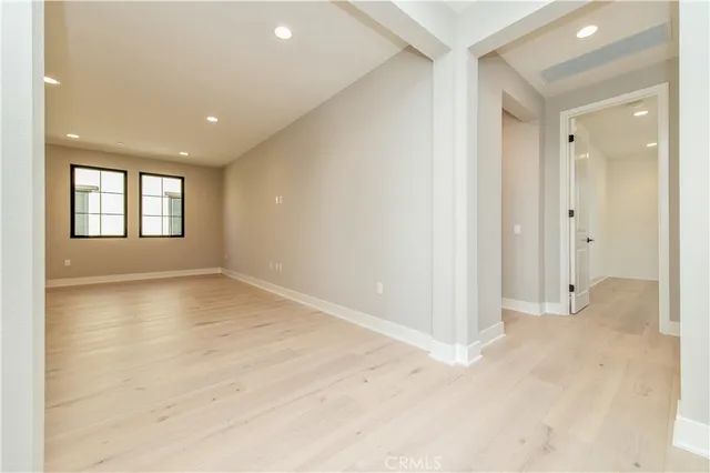 a view of an empty room with window and wooden floor