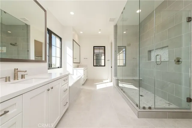 a spacious bathroom with a sink double vanity granite tub shower and a mirror