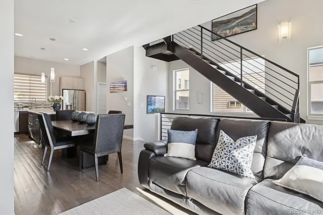 a living room with furniture kitchen view and a wooden floor