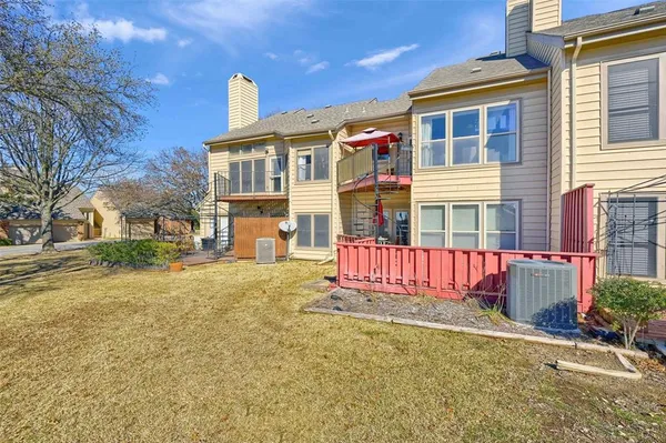 a view of a brick house with large windows and wooden fence
