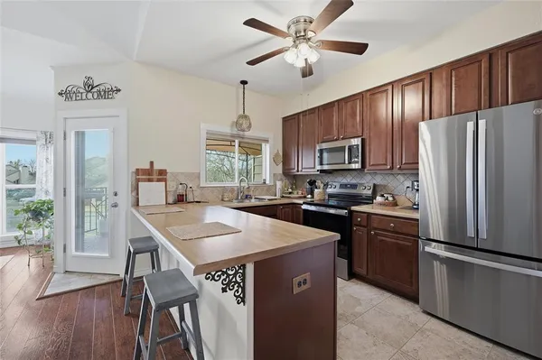 a kitchen with stainless steel appliances granite countertop a refrigerator a stove a sink a stove a dining table and chairs with wooden floor