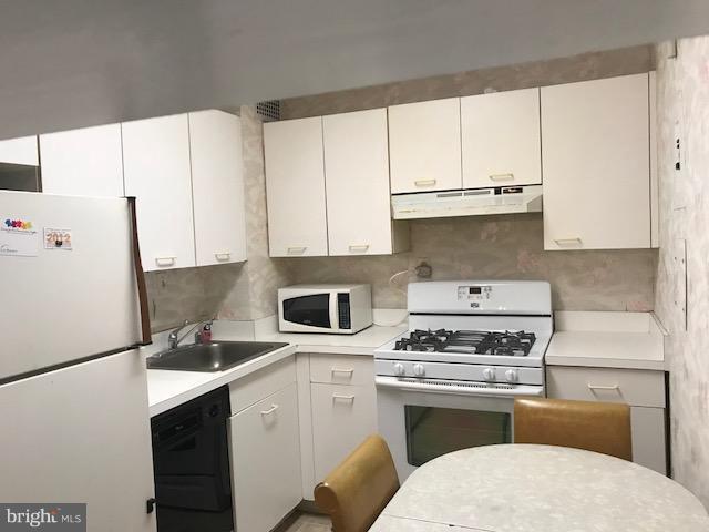 130 Slade Avenue, Unit 411 Baltimore, MD 21208 - Photo 3 of 18 a kitchen with kitchen island white cabinets and white appliances