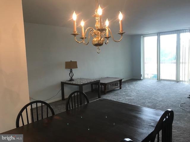 130 Slade Avenue, Unit 411 Baltimore, MD 21208 - Photo 6 of 18 a view of a dining room with furniture a chandelier and wooden floor