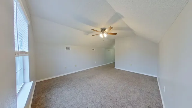 a view of an empty room with a chandelier fan