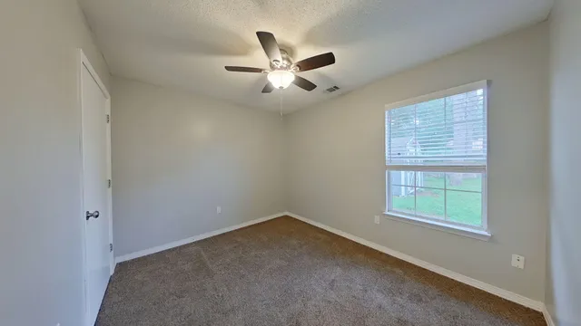 an empty room with a window and ceiling fan