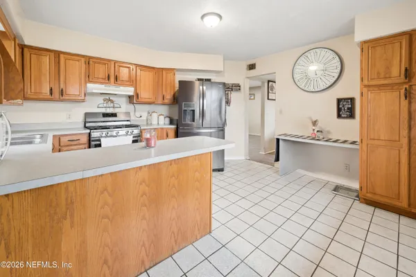 a kitchen with stainless steel appliances granite countertop a stove a sink dishwasher and a refrigerator with wooden cabinets