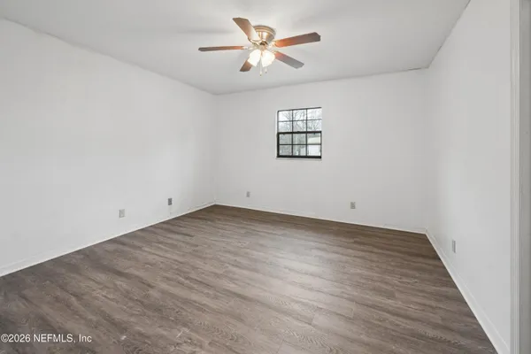an empty room with a window and a ceiling fan