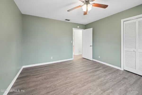 an empty room with a ceiling fan and wooden floor