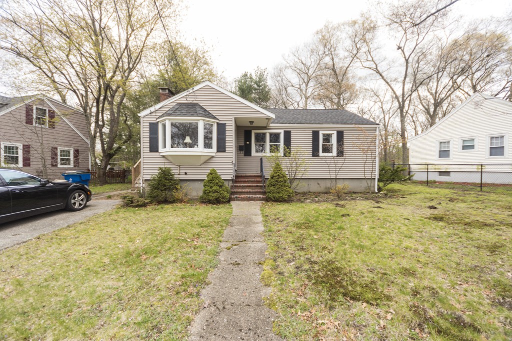 a front view of a house with a yard covered with snow and trees