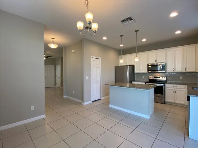 a kitchen with stainless steel appliances granite countertop a refrigerator and a stove top oven