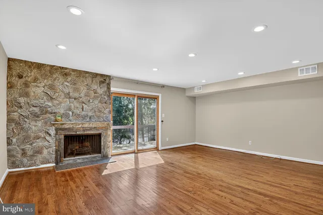 an empty room with wooden floor fireplace and windows