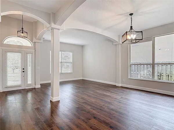 a view of an empty room with wooden floor and a window