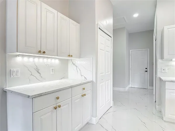 a view of an empty room with kitchen fireplace and a ceiling fan