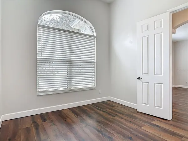 a view of an empty room with wooden floor and a window