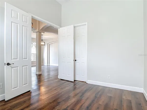 a view of an empty room with wooden floor and a ceiling fan