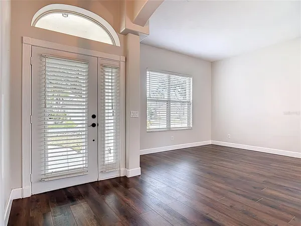 a view of an empty room with wooden floor and a window