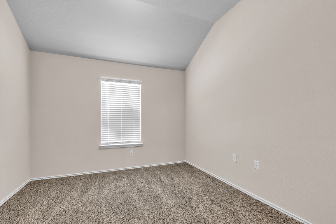 9200 Furman Drive Austin, TX 78747 - Photo 7 of 15 Unfurnished room with carpet flooring and vaulted ceiling