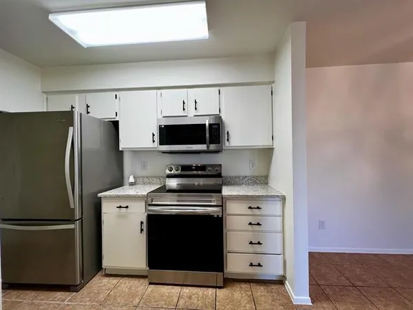 a kitchen with a stainless steel appliances white cabinets and a refrigerator