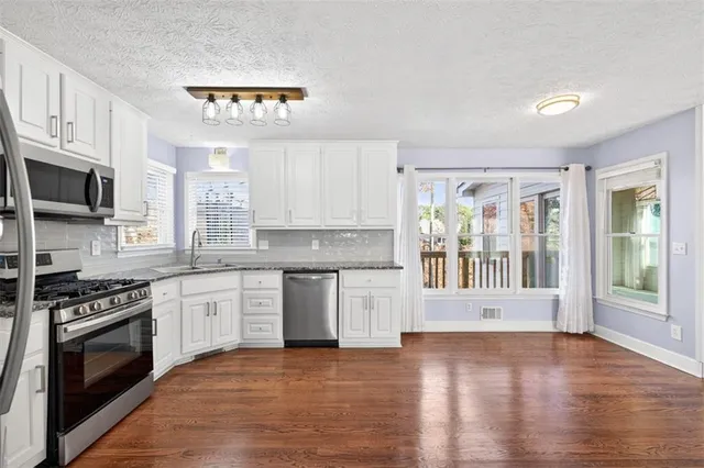 an empty room with windows and chandelier fan