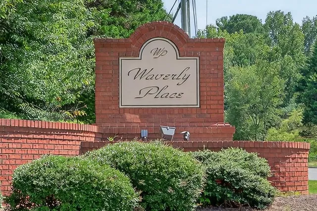 a view of an empty room with wooden floor fireplace and a window