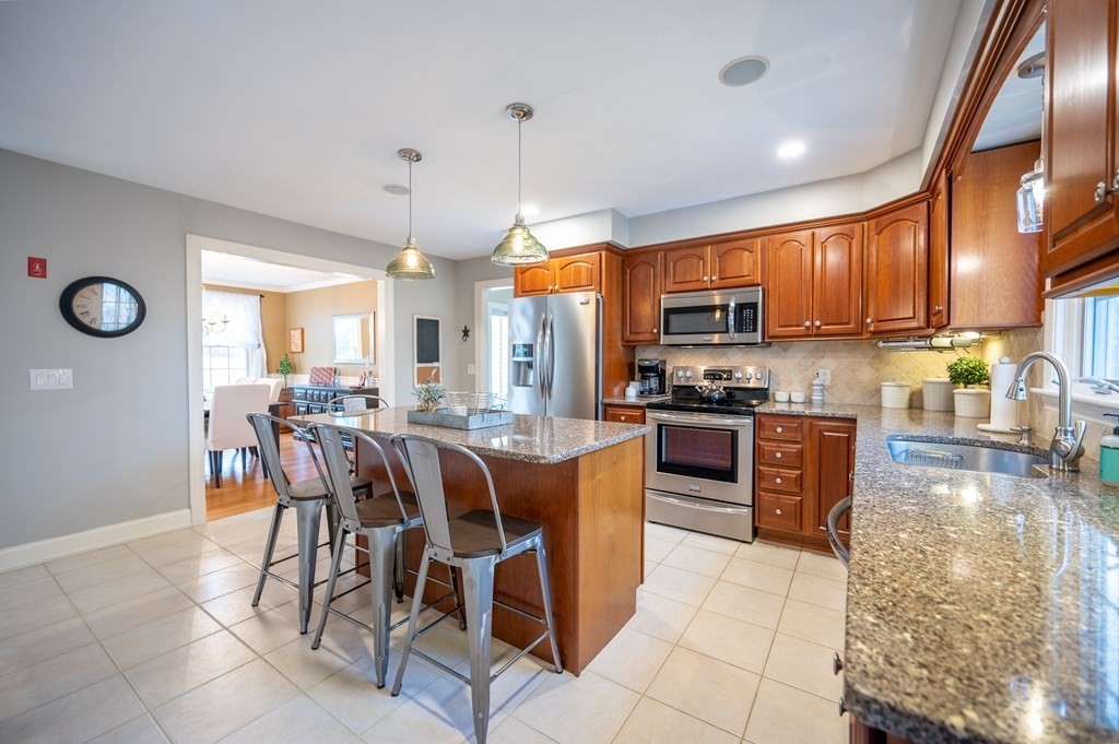 91 Hartness Road Sutton, MA 01590 - Photo 7 of 27 a kitchen with stainless steel appliances granite countertop a stove top oven a sink a dining table and chairs with wooden floor