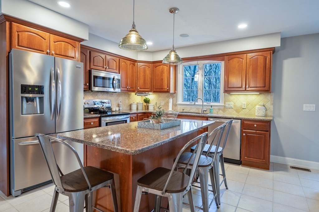 91 Hartness Road Sutton, MA 01590 - Photo 8 of 27 a kitchen with stainless steel appliances granite countertop a stove a refrigerator a sink a dining table and chairs