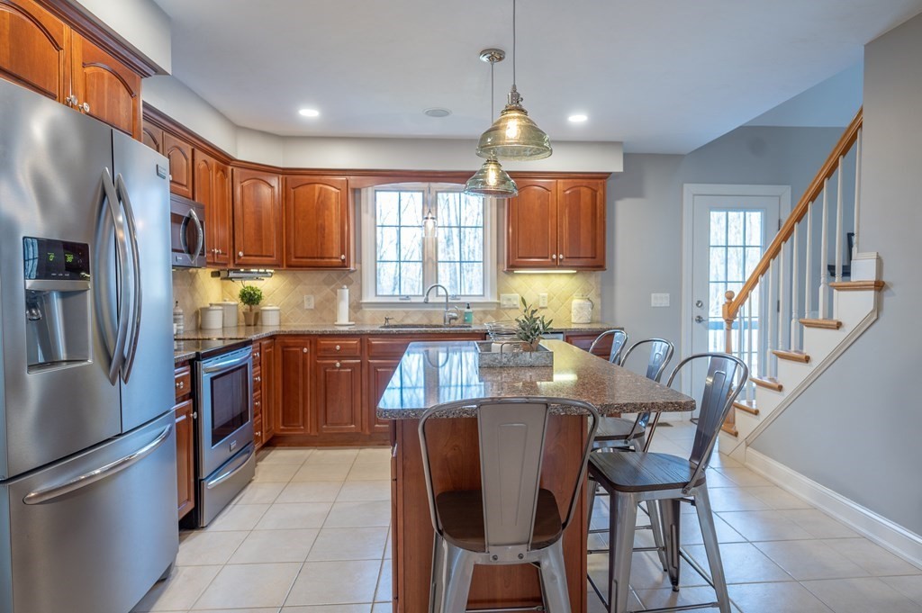 91 Hartness Road Sutton, MA 01590 - Photo 9 of 27 a kitchen with stainless steel appliances granite countertop a stove a refrigerator a sink dishwasher a dining table and chairs with wooden floor