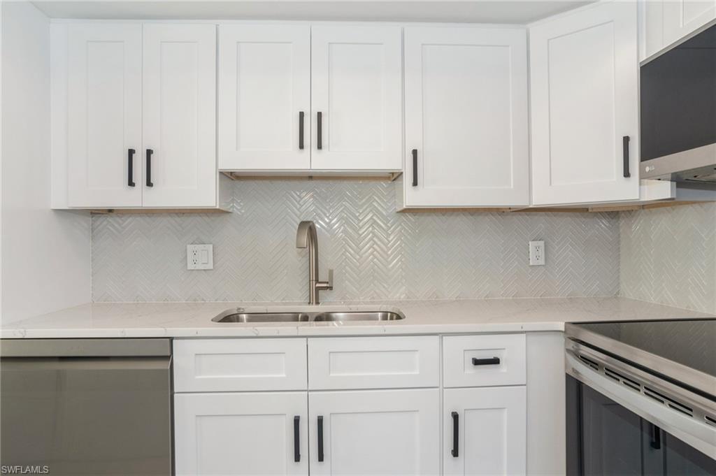 1155 Sandpiper Street, Unit B3 Naples, FL 34102 - Photo 5 of 21 Kitchen with white cabinets, stainless steel appliances, light stone counters, and backsplash