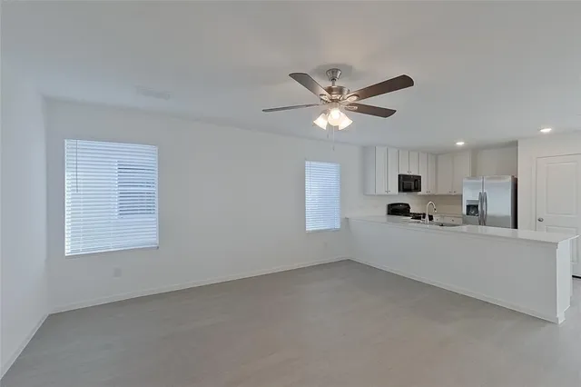 a large white kitchen with stainless steel appliances a sink a stove a microwave a refrigerator and cabinets