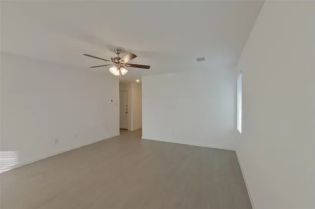 an empty room with chandelier fan and closet