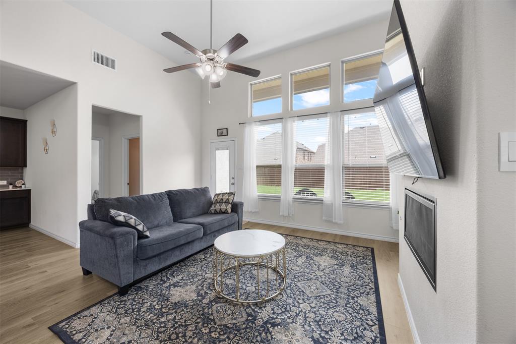 3808 High Country Road Aubrey, TX 76227 - Photo 6 of 36 Vaulted ceilings define this living space featuring wood-finish flooring, a ceiling fan with integrated lighting, and tall windows with blinds