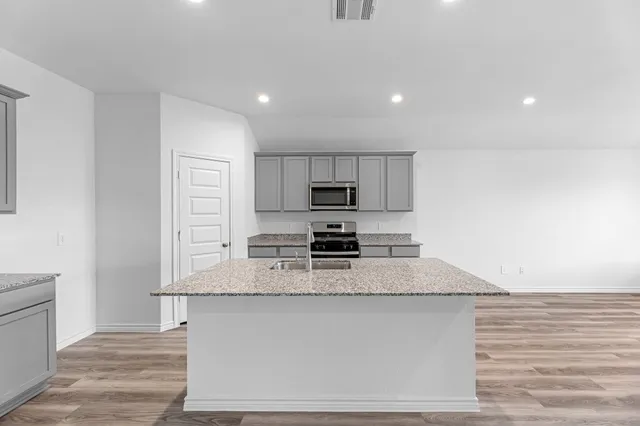 a large kitchen with granite countertop a stove a sink and a microwave