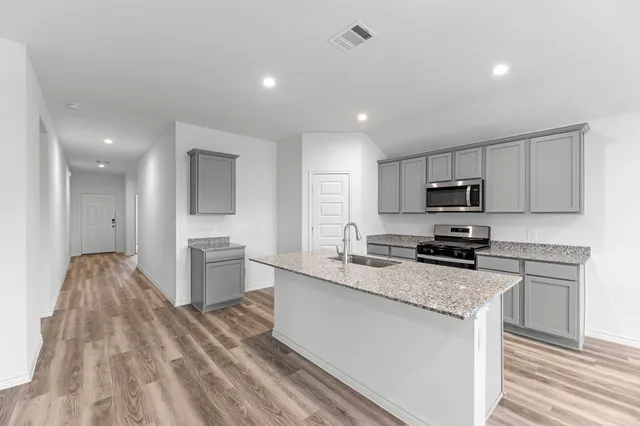 a kitchen with granite countertop a sink stove and refrigerator