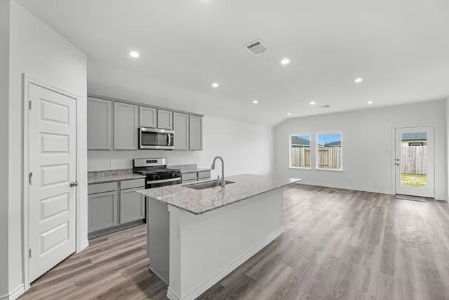 a kitchen with granite countertop stainless steel appliances a stove refrigerator sink and cabinets