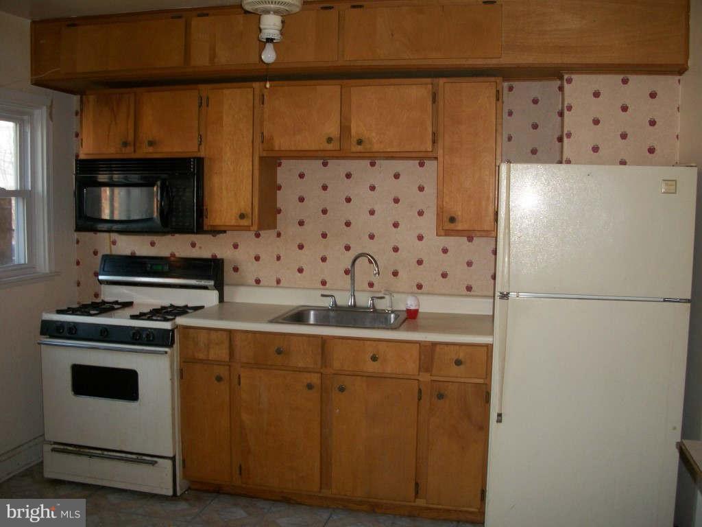 15 Warren Road Baltimore, MD 21221 - Photo 4 of 10 a kitchen with granite countertop a stove a sink and a microwave