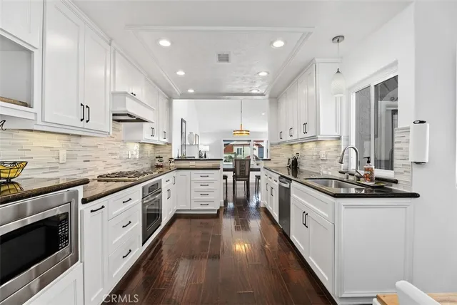 a kitchen with stainless steel appliances granite countertop a stove top oven a sink dishwasher and a refrigerator