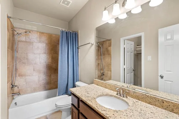 a bathroom with a granite countertop sink a toilet a mirror a bathtub and shower