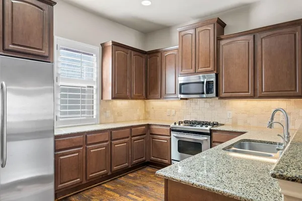 a kitchen with stainless steel appliances granite countertop a sink stove and refrigerator