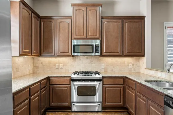 a kitchen with stainless steel appliances granite countertop white cabinets and a stove top oven