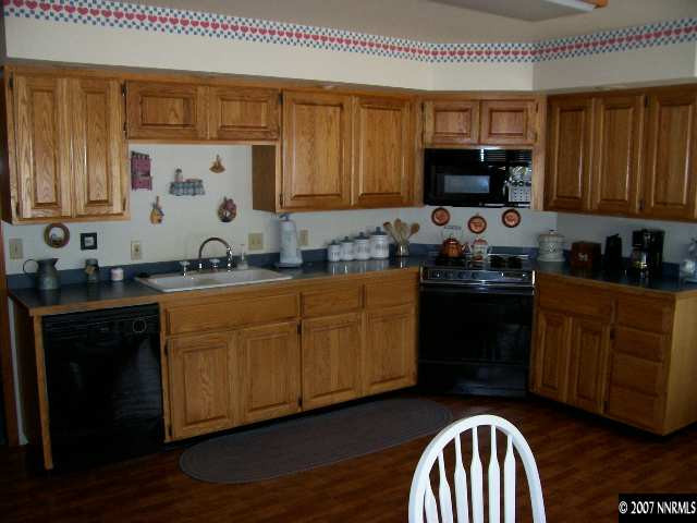 3368 Rice Road Fallon, NV 89406 - Photo 4 of 6 a kitchen with stainless steel appliances granite countertop a sink dishwasher stove and microwave with wooden floor